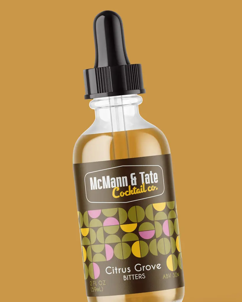 A 2oz bottle of McMann & Tate Cocktail Co's Cirtus Grove Bitters, with white and yellow text and green/pink/yellow designs, on a dark brown background.